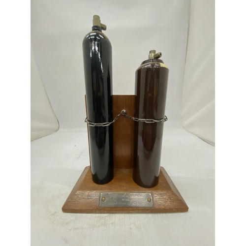 16 - TWO MINIATURE GAS CYLINDERS ON A WOODEN STAND PRESENTED BY ALL AT B.O.C. AS A RETIREMENT GIFT