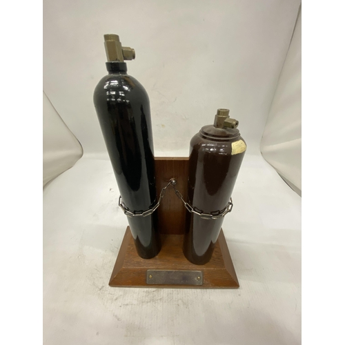 16 - TWO MINIATURE GAS CYLINDERS ON A WOODEN STAND PRESENTED BY ALL AT B.O.C. AS A RETIREMENT GIFT