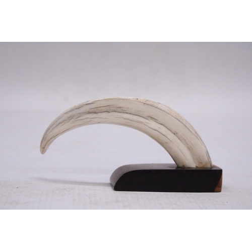 183 - A CARVED WILD BOAR TUSK ON A WOODEN PLINTH