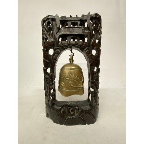 2 - A CHINESE TEMPLE BELL DECORATED WITH DRAGONS SUPPORTED WITHIN A CARVED HARD WOOD STAND