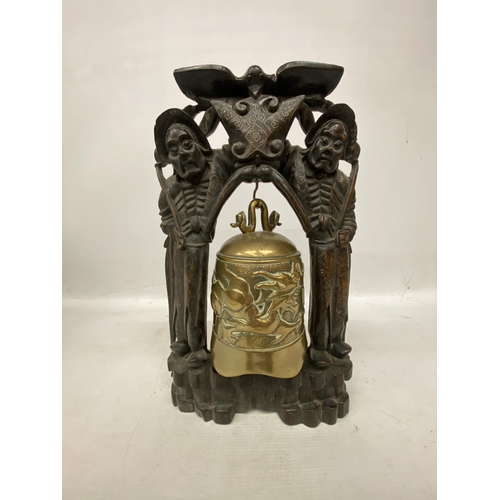 44 - A CHINESE BUDDHIST TEMPLE BELL DECORATED WITH DRAGONS SUPPORTED WITHIN A CARVED HARD WOOD STAND WITH... 