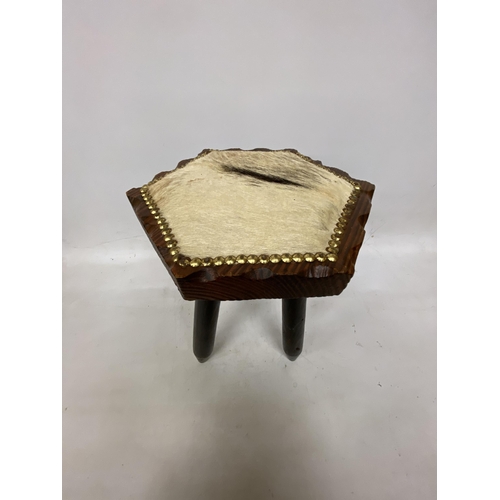 67 - A THRRE LEGGED MILKING STOOL WITH COW HIDE SEAT HEIGHT 41CM