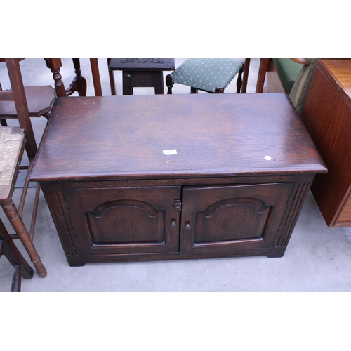 2887 - AN OAK JACOBEAN STYLE LOW CUPBOARD WITH TWO CARVED PANEL DOORS, 33