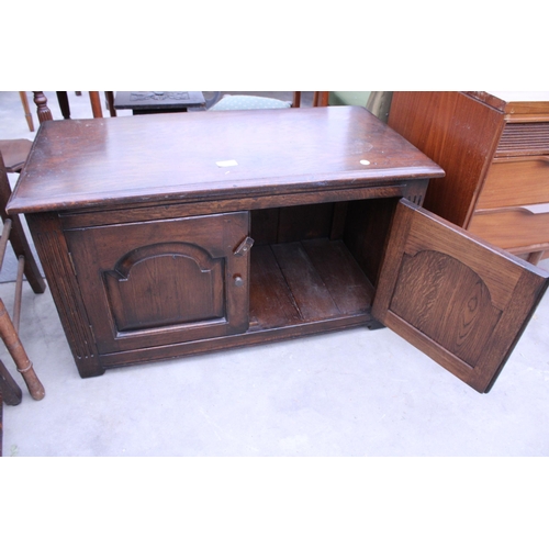 2887 - AN OAK JACOBEAN STYLE LOW CUPBOARD WITH TWO CARVED PANEL DOORS, 33