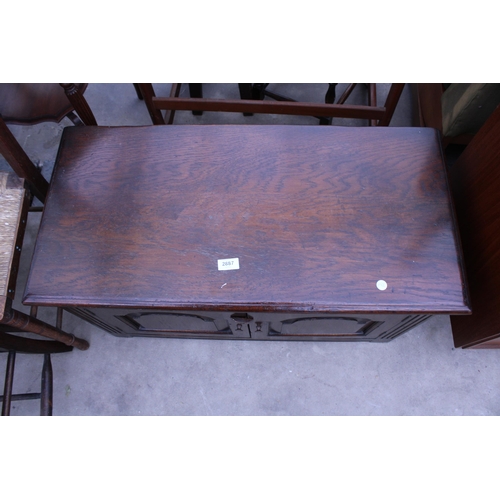 2887 - AN OAK JACOBEAN STYLE LOW CUPBOARD WITH TWO CARVED PANEL DOORS, 33