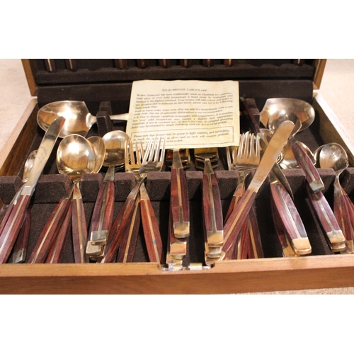 989 - A BRONZE AND WOOD CANTEEN OF CUTLERY IN A TEAK BOX