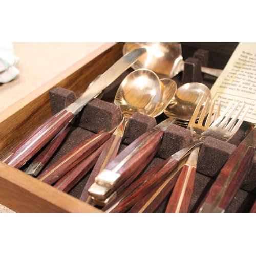 989 - A BRONZE AND WOOD CANTEEN OF CUTLERY IN A TEAK BOX