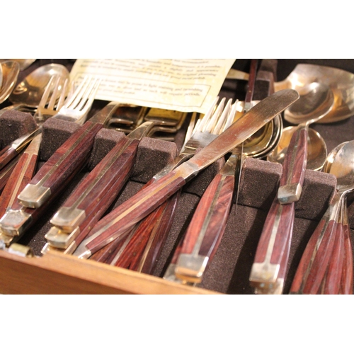 989 - A BRONZE AND WOOD CANTEEN OF CUTLERY IN A TEAK BOX