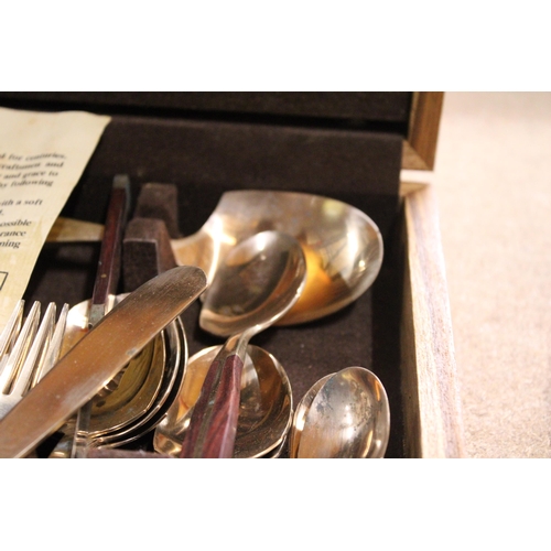 989 - A BRONZE AND WOOD CANTEEN OF CUTLERY IN A TEAK BOX