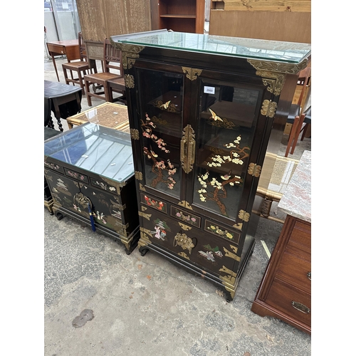 2660 - AN ORIENTAL EBONISED TWO DOOR GLAZED CABINET WITH THREE DRAWERS AND CUPBOARDS TO BASE, ALL WITH APPL... 