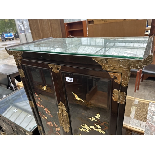 2660 - AN ORIENTAL EBONISED TWO DOOR GLAZED CABINET WITH THREE DRAWERS AND CUPBOARDS TO BASE, ALL WITH APPL... 