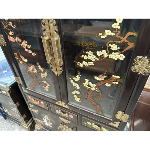 2660 - AN ORIENTAL EBONISED TWO DOOR GLAZED CABINET WITH THREE DRAWERS AND CUPBOARDS TO BASE, ALL WITH APPL... 