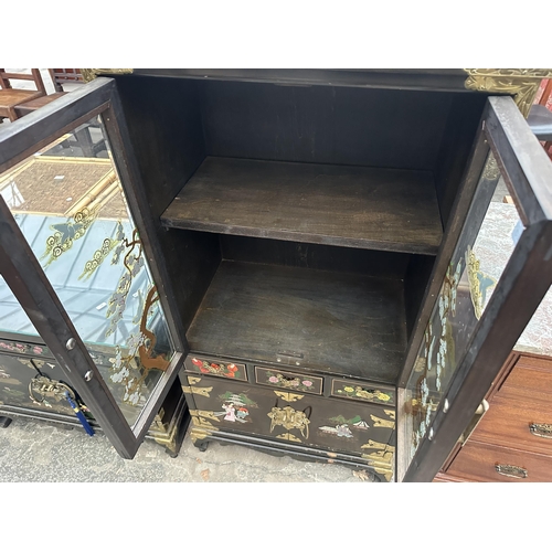 2660 - AN ORIENTAL EBONISED TWO DOOR GLAZED CABINET WITH THREE DRAWERS AND CUPBOARDS TO BASE, ALL WITH APPL... 