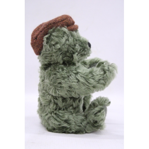 108 - A SMALL GREEN STEIFF TEDDY BEAR WITH A FLAT CAP AND BUTTON TO HIS EAR, HEIGHT 25CM