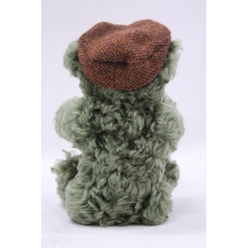 108 - A SMALL GREEN STEIFF TEDDY BEAR WITH A FLAT CAP AND BUTTON TO HIS EAR, HEIGHT 25CM