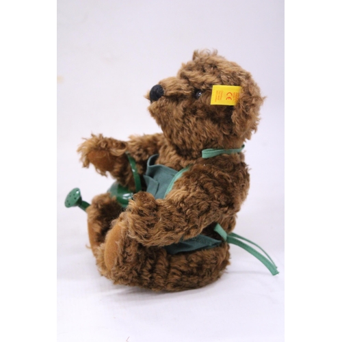 137 - A STEIFF 'GARDENER' TEDDY BEAR WITH APRON AND WATERING CAN AND BUTTON IN THE EAR