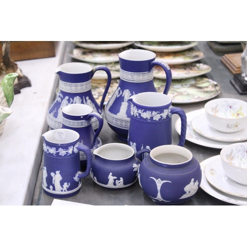 198 - SEVEN PIECES OF DARK BLUE WEDGWOOD JASPERWARE TO IONCLDE SIX JUGS OF VARYING SIZES AND A SUGAR BOWL