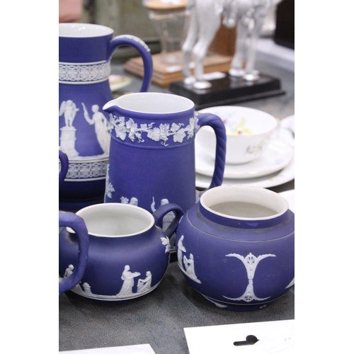 198 - SEVEN PIECES OF DARK BLUE WEDGWOOD JASPERWARE TO IONCLDE SIX JUGS OF VARYING SIZES AND A SUGAR BOWL