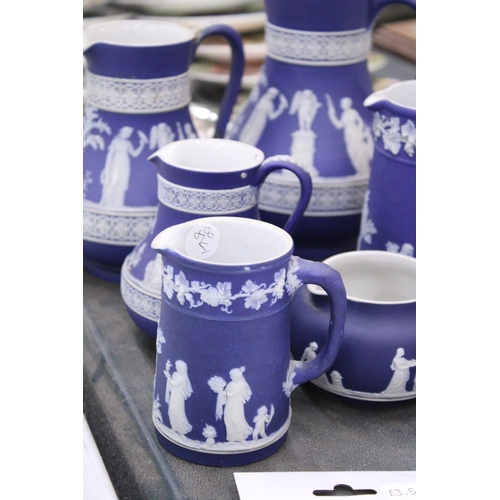 198 - SEVEN PIECES OF DARK BLUE WEDGWOOD JASPERWARE TO IONCLDE SIX JUGS OF VARYING SIZES AND A SUGAR BOWL