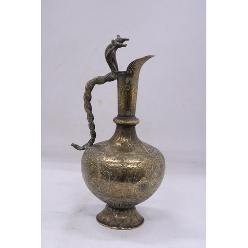 79 - A DECORATIVE BRASS JUG WITH A LONG SPOUT AND AN ORNATE HANDLE IN THE FORM OF A PAIR OF COBRA'S