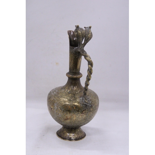 79 - A DECORATIVE BRASS JUG WITH A LONG SPOUT AND AN ORNATE HANDLE IN THE FORM OF A PAIR OF COBRA'S