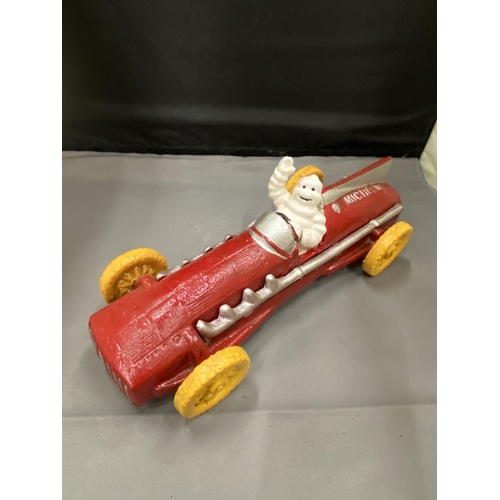 20 - A CAST MICHELIN MAN AVERTSING FIGURE DEPICTING MICHELIN MAN IN A RED RACING CAR 25CM LONG