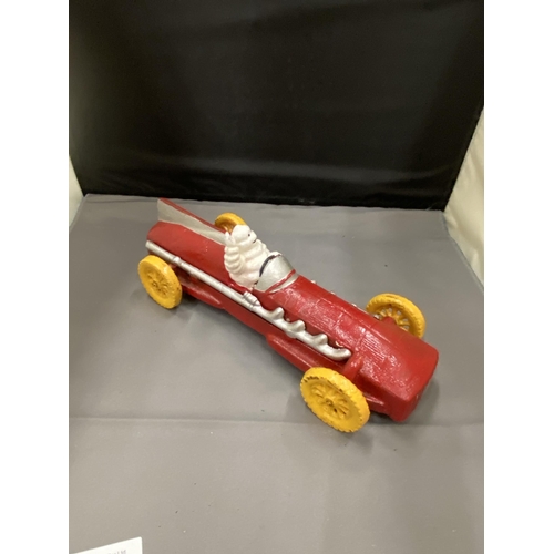 20 - A CAST MICHELIN MAN AVERTSING FIGURE DEPICTING MICHELIN MAN IN A RED RACING CAR 25CM LONG