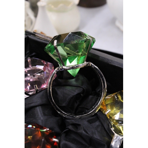 143 - A BOXED SET OF SIX NAPKIN RINGS WITH LARGE STONES TO LOOK LIKE SOLITAIRE RINGS