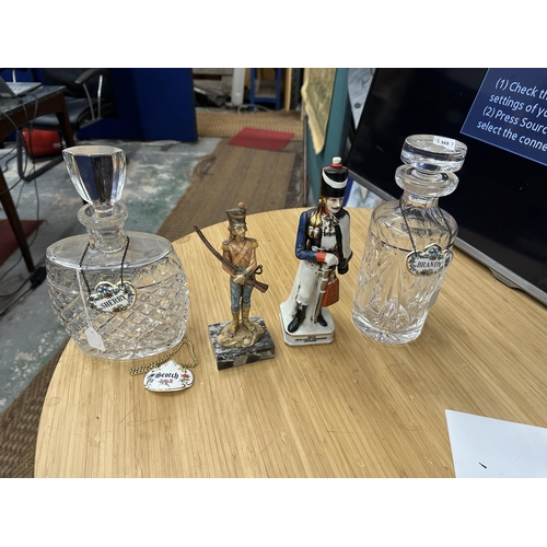 85 - TWO GLASS DECANTERS WITH THREE CERAMIC DECANTER LABELS, A RESIN SOLDIER ON A CARRARA MARBLE BASE AND... 