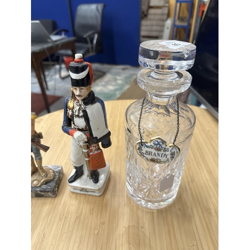 85 - TWO GLASS DECANTERS WITH THREE CERAMIC DECANTER LABELS, A RESIN SOLDIER ON A CARRARA MARBLE BASE AND... 