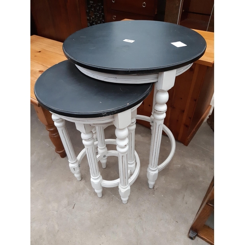 2625 - A WHITE AND BLACK NEST OF THREE TABLES ON FLUTED LEGS