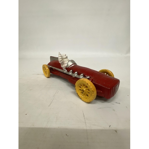 107 - A CAST MICHELIN MAN AVERTSING FIGURE DEPICTING MICHELIN MAN IN A RED RACING CAR 25CM LONG