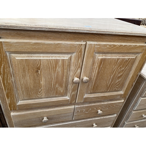 2792 - A LIMED OAK T.V. CABINET WITH SLIDING TOP DOORS AND DRAWERS TO BASE, 39.5