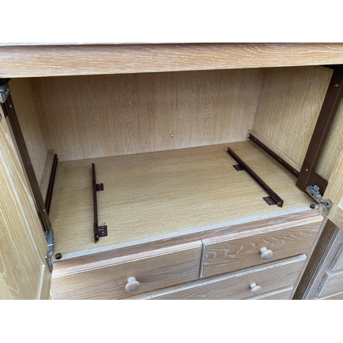 2792 - A LIMED OAK T.V. CABINET WITH SLIDING TOP DOORS AND DRAWERS TO BASE, 39.5