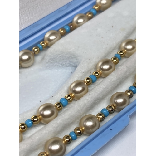 638 - A STRING OF PEARLS WITH BLUE AND YELLOW METAL BEADS AND A MATCHING BRACELET IN A PRESENTATION BOX