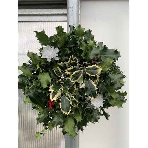 25 - TWO CHRISTMAS WREATHS WITH HOLLY, RIBBON AND CHRISTMAS ACCESSORIES ON A MOSS RING. APPROX 30CM IN DI... 