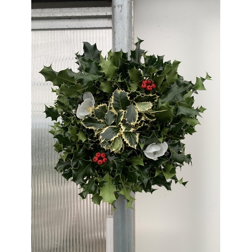 25 - TWO CHRISTMAS WREATHS WITH HOLLY, RIBBON AND CHRISTMAS ACCESSORIES ON A MOSS RING. APPROX 30CM IN DI... 