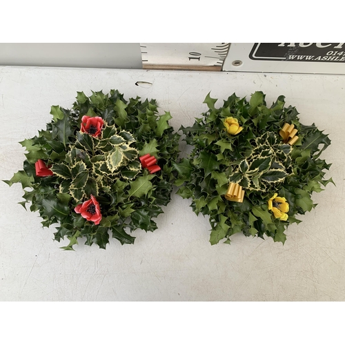 31 - TWO CHRISTMAS WREATHS WITH HOLLY, RIBBON AND CHRISTMAS ACCESSORIES ON A MOSS RING. APPROX 30CM IN DI... 