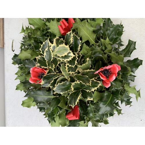 31 - TWO CHRISTMAS WREATHS WITH HOLLY, RIBBON AND CHRISTMAS ACCESSORIES ON A MOSS RING. APPROX 30CM IN DI... 