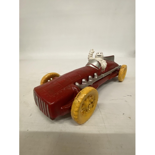 107 - A CAST MICHELIN MAN AVERTSING FIGURE DEPICTING MICHELIN MAN IN A RED RACING CAR 25CM LONG