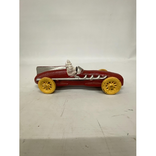 107 - A CAST MICHELIN MAN AVERTSING FIGURE DEPICTING MICHELIN MAN IN A RED RACING CAR 25CM LONG