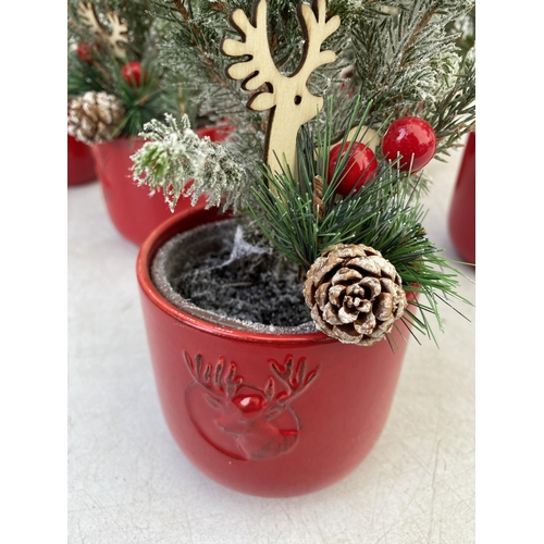 19 - EIGHT CHRISTMAS CONIFERS WITH CHRISTMAS DEER, BERRIES AND FIR CONES ACCESSORIES IN RED CERAMIC DEER ... 