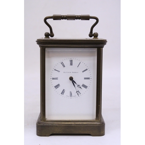 265 - A MATTHEW NORMAN BRASS CARRIAGE CLOCK WIT WHITE ENAMEL FACE, ROMAM NUMERALS AND VISUAL ESCAPEMENT