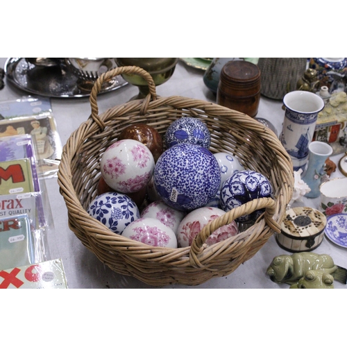 278 - A COLLECTION OF VARIOUS SIZES OF PATTERNED CERAMIC BALLS IN A BASKET