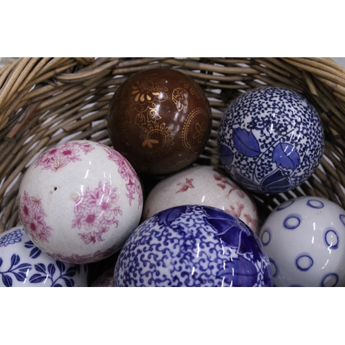 278 - A COLLECTION OF VARIOUS SIZES OF PATTERNED CERAMIC BALLS IN A BASKET