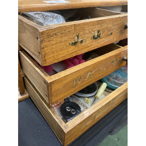 4 - A VINTAGE THREE DRAWER SEWING CABINET WITH ADVERTISING LABELS AND CONTENTS