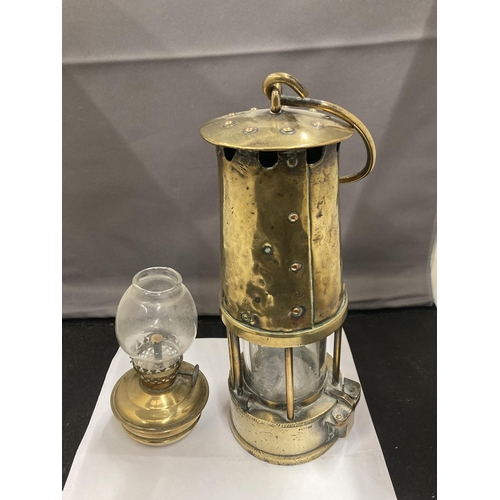 85 - TWO BRASS LAMPS TO INCLUDE A VICTORIAN MINIATURE PARAFFIN LAMP WITH GLASS FUNNEL AND A PROJECTOR LAM... 