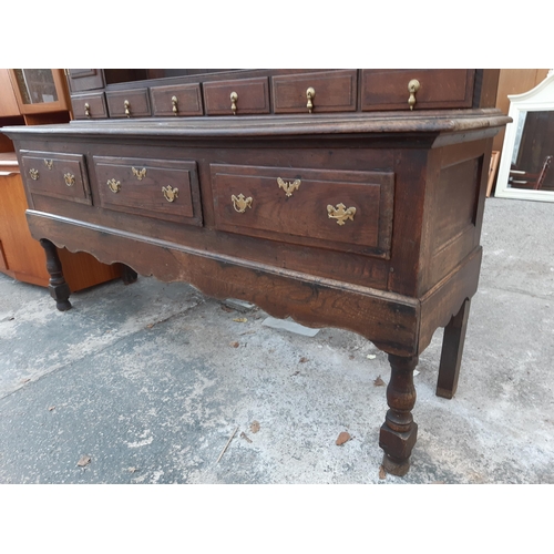 2889 - A GEORGIAN OAK DRESSER WITH THREE DRAWERS TO BASE AND PLATE RACK ENCLOSING TWO CUPBOARDS WITH H BRAS... 