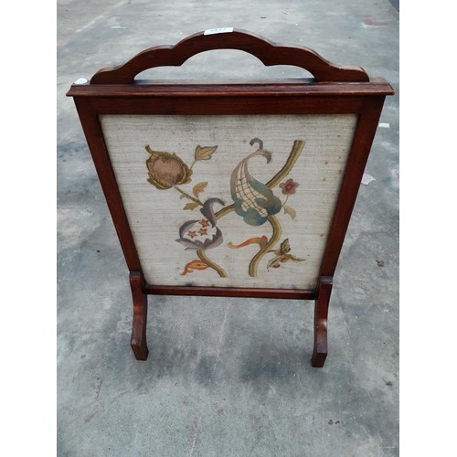 2877 - AN ART NOUVEAU MAHOGANY FIRESCREEN WITH INSET WOOLWORK PANEL DEPCITING FLOWERS