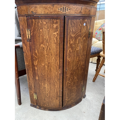 2634 - A GEORGE III OAK AND CROSSBANDED BOW FRONTED CORNER CUPBOARD WITH H BRASS HINGES, 26.5